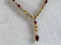 Close view of the garnet and citrine stones with diamond accents in the Y-drop section of the necklace.