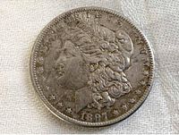 Obverse side of the 1897 Morgan Silver Dollar coin showing Lady Liberty profile, date 1897, and surrounding stars and inscriptions.