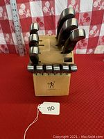 Knife set in wooden block showing the top view of six larger knives and the block with J.A. Henckels logo.