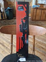 Front view of vertical painting on board depicting a black silhouette of a saxophone player under a hanging sign reading 'Jazz Playhouse' on a red background, signed by Ricco Rideaux.
