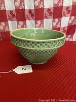 Front angled view of green glazed Art Deco style mixing bowl with embossed checkerboard pattern on exterior.