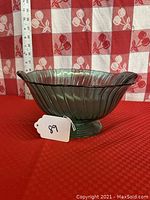 Side view showing the ribbed swirl pattern, teal color, and flared wavy rim of the glass bowl. Ruler for scale indicating approximately 5.5 inches tall.