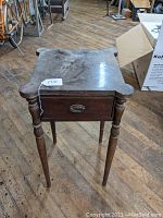 Front view of the mahogany one drawer stand with cookie corners, showing the drawer with brass pull and surface condition.