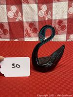 Teal green glass swan figurine shown from front angle on red patterned backdrop.