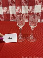 Pair of Heisey Orchid cordial stem wine glasses on a red and white checkered surface showing full glasses