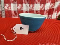 Blue Pyrex mixing bowl showing side profile with red checked background