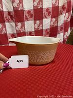 Side view of the Pyrex Woodland pattern Cinderella casserole bowl showing floral design on light brown background with white interior and spout.