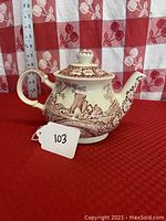 Full side view of the ceramic teapot showing scenic pattern with castle, handle, and knob on lid.