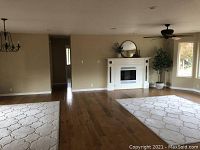 Two beige area rugs laid out in living room over hardwood floors