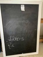 Framed chalk board showing chalk writing and white frame.