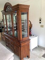Full view of the china cabinet showing the wood finish, glass doors, and lower drawers and cabinets.