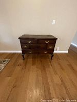 Front view of vintage wood dresser showing drawer configuration, handles, and leg carving detail.