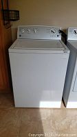 Full front view of the white Kenmore Series 400 top load washer next to a dryer. The washer appears intact with a clean top and control panel facing front.