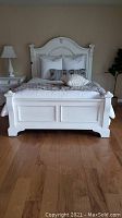Front view of the white painted wood bed frame with decorative headboard and footboard.
