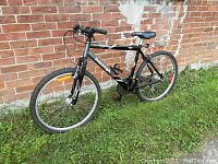 Full side view of the Raleigh Tomahawk bike leaning against brick wall