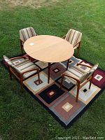 Overview of round teak table and four matching chairs on patterned rug