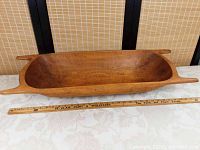 Full side view of entire pine dough bowl with wooden ruler laid in front showing full length
