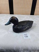 Photo of entire wooden duck decoy, showing general shape and wear on black painted body with blue bill.