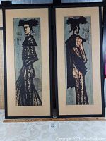 Two framed lithographs side by side on table with ruler at front showing overall presentation and scale.