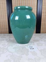 Full view of the moss green vase showing its rounded shape and glossy finish.