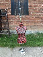 Full view of floor lamp with dress form mannequin torso covered in buttons topped with black lampshade.