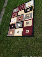 Full view of rug laid flat on grass showing overall pattern and colors