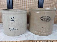 Two antique stoneware crocks side by side on table