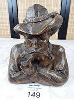 Front view of the hand carved wooden man smoking a pipe, showing detailed facial features and crossed arms.