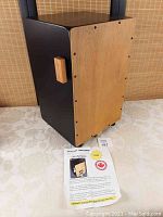Full view of wooden cajon drum box showing front natural wood strike panel, wooden side handle.