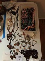View of assorted costume jewelry spread on a table including necklaces, earrings, brooches, and pendants