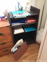 Photo of small dark wood shelf loaded with language books, binders, and two glass decorative items on top