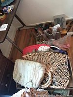 Photo of assorted handbags including woven, fabric, and other vintage styles placed on floor under table.