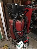 Red Craftsman air compressor showing tank, motor, and hose with garage background