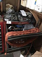 Overview of red tool chest with orange extension cord on top and various power and hand tools.