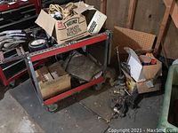 Garage cart loaded with gloves, rope, hand tools, tarp, rags, and two boxes containing miscellaneous items.