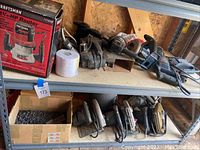 Shelves with multiple power tools such as circular saws and a boxed Craftsman router.