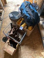 View of blue Ryobi tool bag, metal bucket with hardware, cardboard boxes with assorted tools and painting supplies, metal basket with tool belt