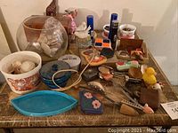 Wide view of table with assorted seashells, figurines, vintage decor, and small collectibles scattered across it