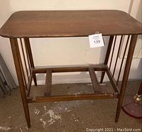 Front angled view of the mid-century wooden credenza table showing its rectangular top with rounded corners and slender tapered legs.