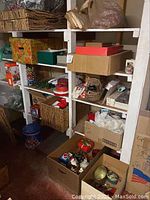 Shelves and boxes filled with various Christmas and holiday decorations in storage including wreaths, tins, and figurines.