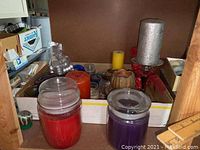 Photo showing jar candles in red and purple, large silver glittery pillar candle and other assorted pillar and decorative candles.