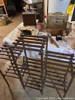Wooden multi-tier plant stand in front of a table with various decor items.