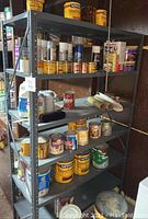 Photo showing metal shelves with various paint cans and supplies placed on five shelves, demonstrating height and capacity of the shelf.