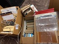 Four cardboard boxes filled with postcards, albums, and miscellaneous papers including legal forms and cables in some boxes.