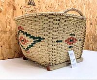 Front angle of basket showing shape, color, geometric design, and wooden base.