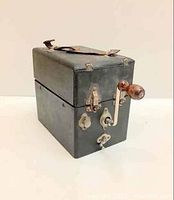 Gramophone closed in black leatherette-covered case showing carry handle and metal latches