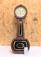 Full front view of wooden drop-style clock against plywood background