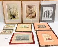 Nine framed pieces of antique artwork arranged on floor including watercolours, etchings, and prints.