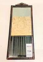 Front view of antique rectangular mirror with ornamental wooden frame showing discoloration on reflective surface.