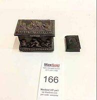 Full view of antique metal jewelry box with ornate cherub relief and separate small booklet container